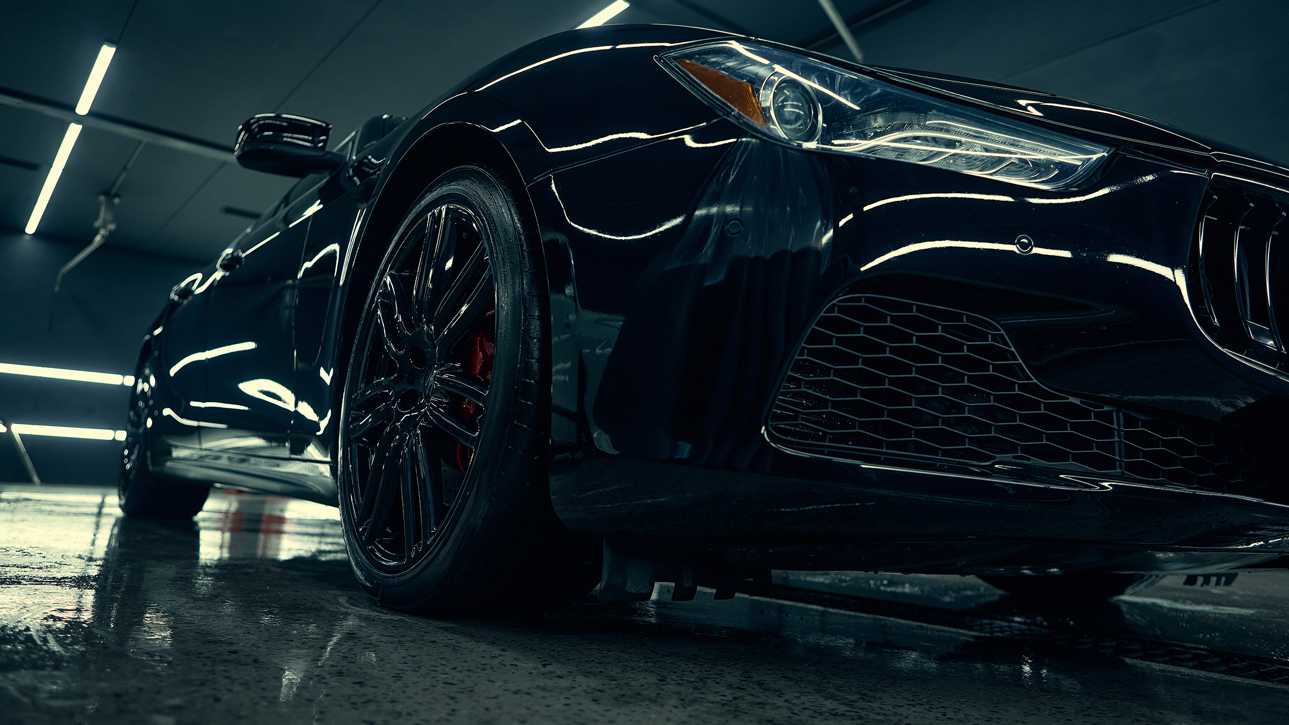 Luxury black car front view with glossy reflections in detailing studio. Concept of premium vehicle aesthetics, maintenance quality, and showroom-level presentation.