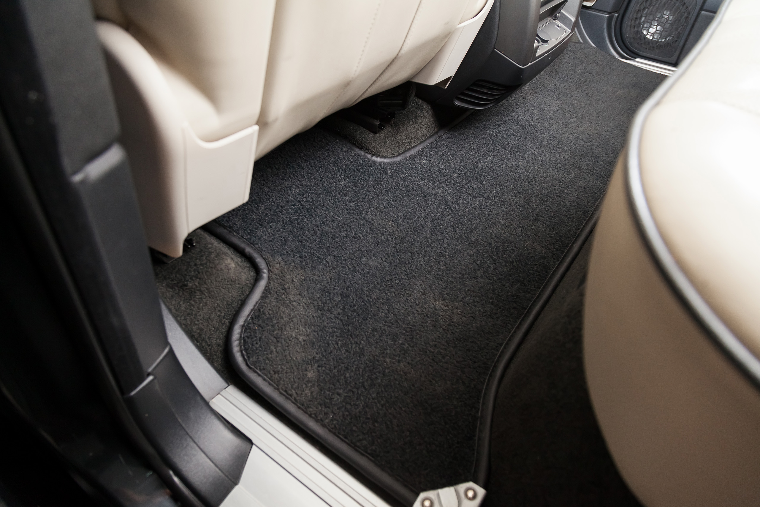Clean car floor mats of black carpet under rear passenger seat in the workshop for the detailing vehicle before dry cleaning. Auto service industry. Interior of sedan.