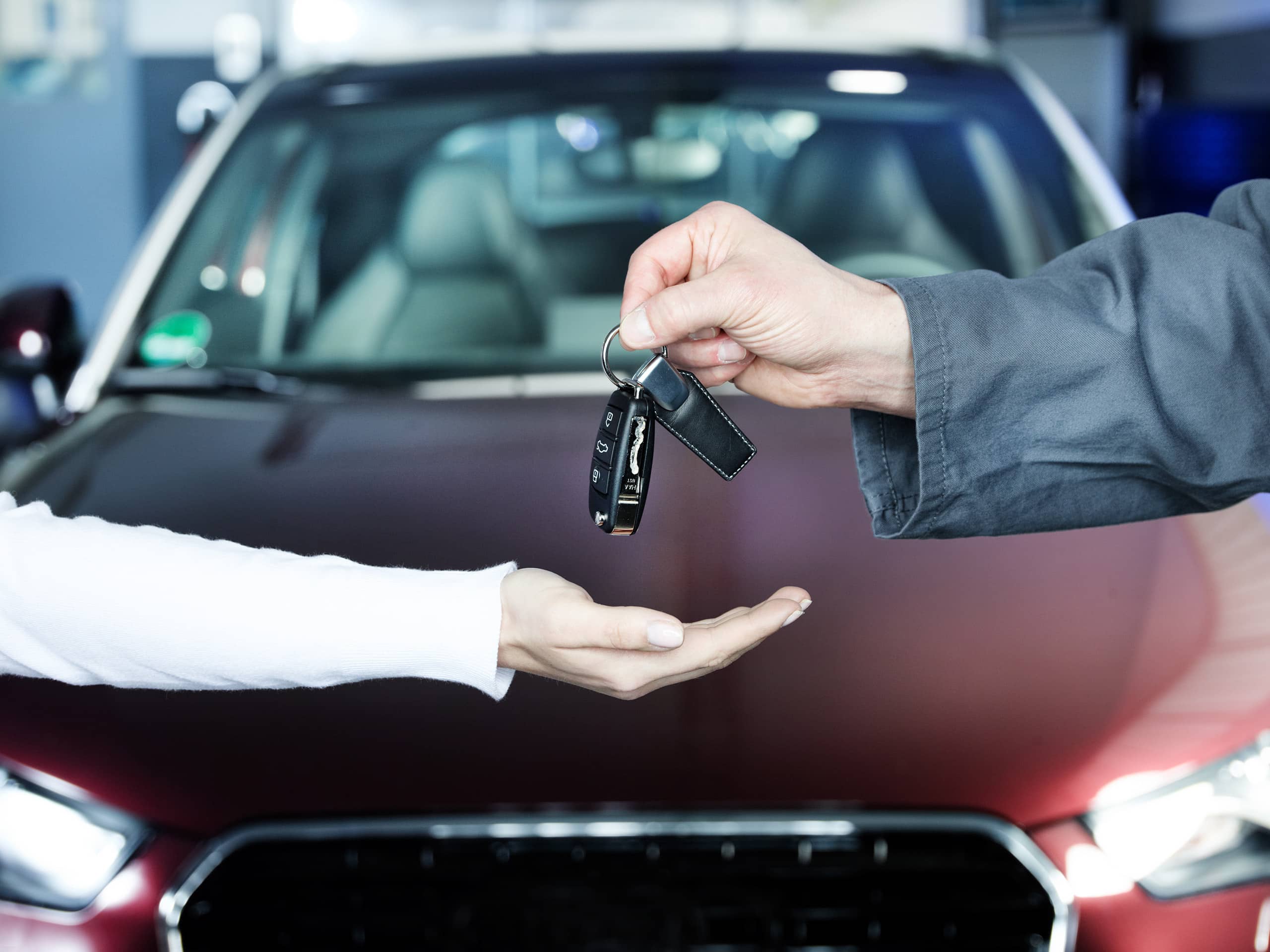 Key delivery between customer and mechanic in front of new car