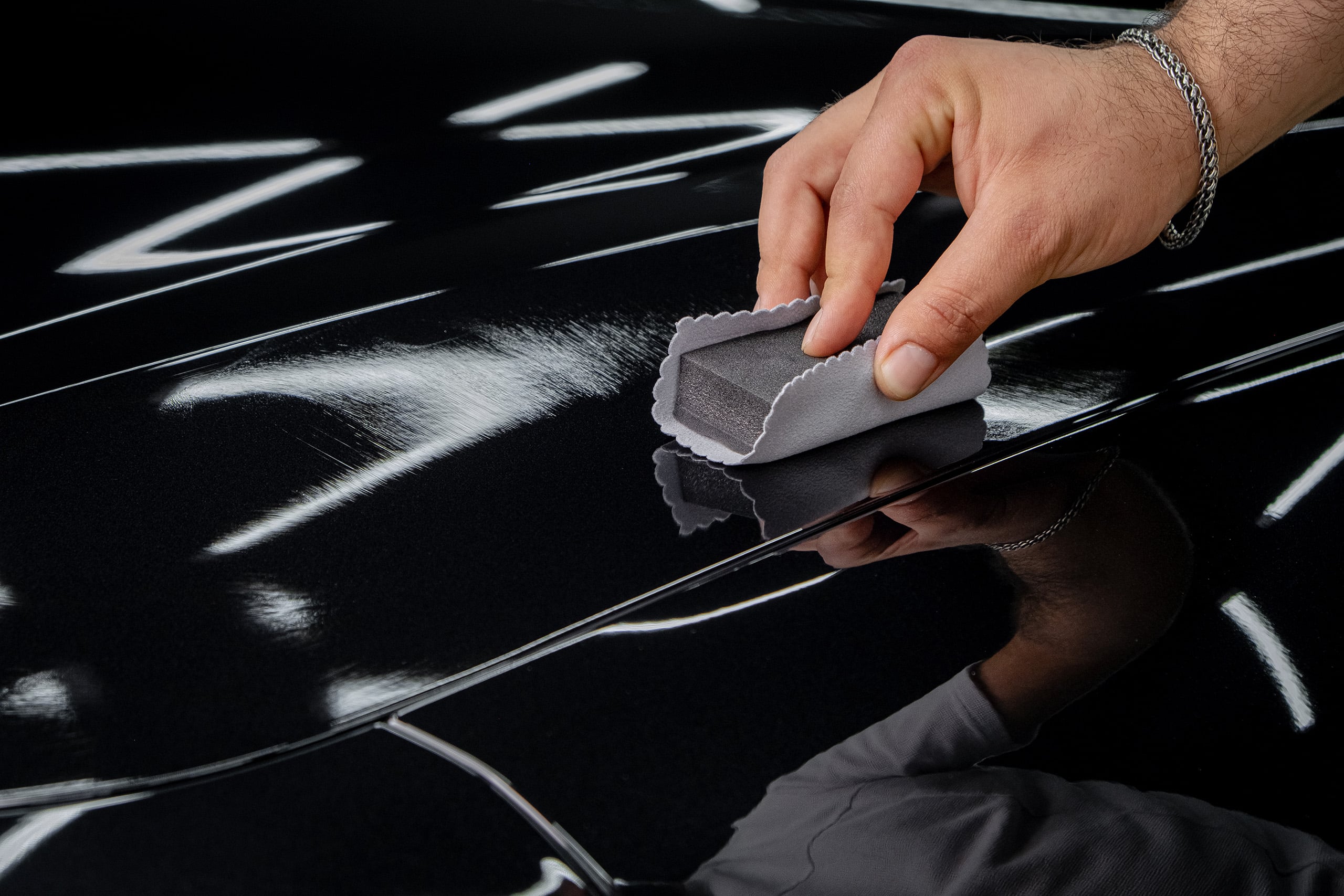 An auto service worker applying a nanocoating to a car part. Cer
